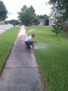 Tomy adjusts a sprinkler head in a Cedar Hill TX front yard